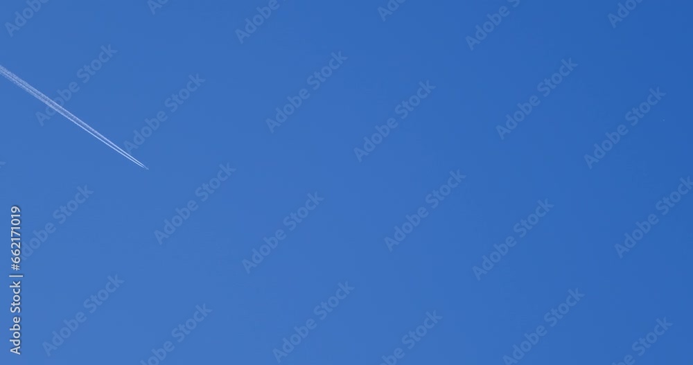 Airplane flying on deep blue sky with chemical direction trails, view from a distance Airplane flying on deep blue sky with chemical direction trails, view from a distance