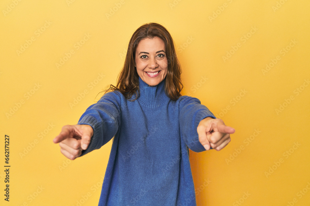 Middle-aged caucasian woman on yellow cheerful smiles pointing to front. Middle-aged caucasian woman on yellow cheerful smiles pointing to front.