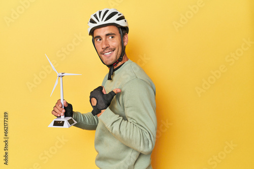 Cyclist with windmill, clean transport theme points with thumb finger away, laughing and carefree.