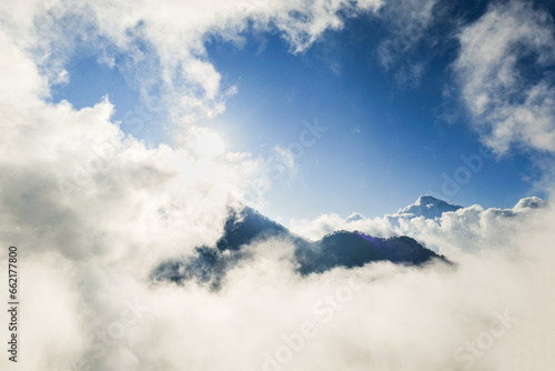 mountain peak covered by sea of cloud with blue sky in the morning at Mount Rinjani, Lombok, Indonesia. Atmospheric mountain nature photo for adventure, trekking, mountaineering concept
