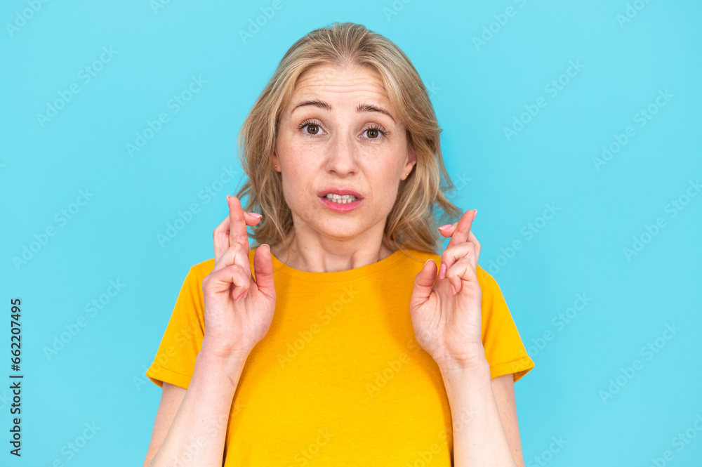 Obraz premium Worried young woman showing fingers crossed gesture