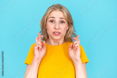 Worried young woman showing fingers crossed gesture