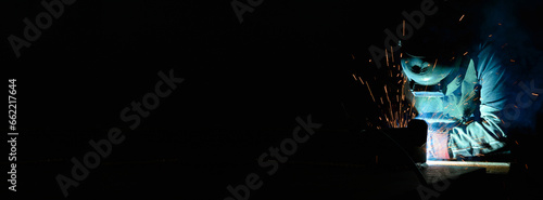 Welder uses torch to make sparks during manufacture of metal equipment photo