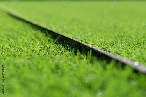 Artificial grass close-up. Artificial turf background. Short cut real grass on the edge of the pitch in the stadium. Evergreen artificial grass close-up photo