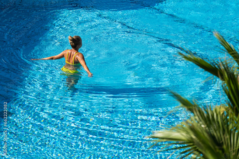 A woman swims in the pool. Girl in the outdoor pool. Outdoor pool.