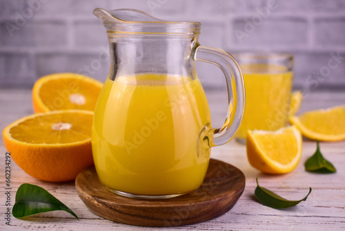 Orange juice in a glass decanter and fresh oranges.