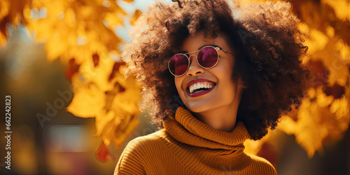 Beautiful smiling black woman walking in the park with autumn leaves, fashion