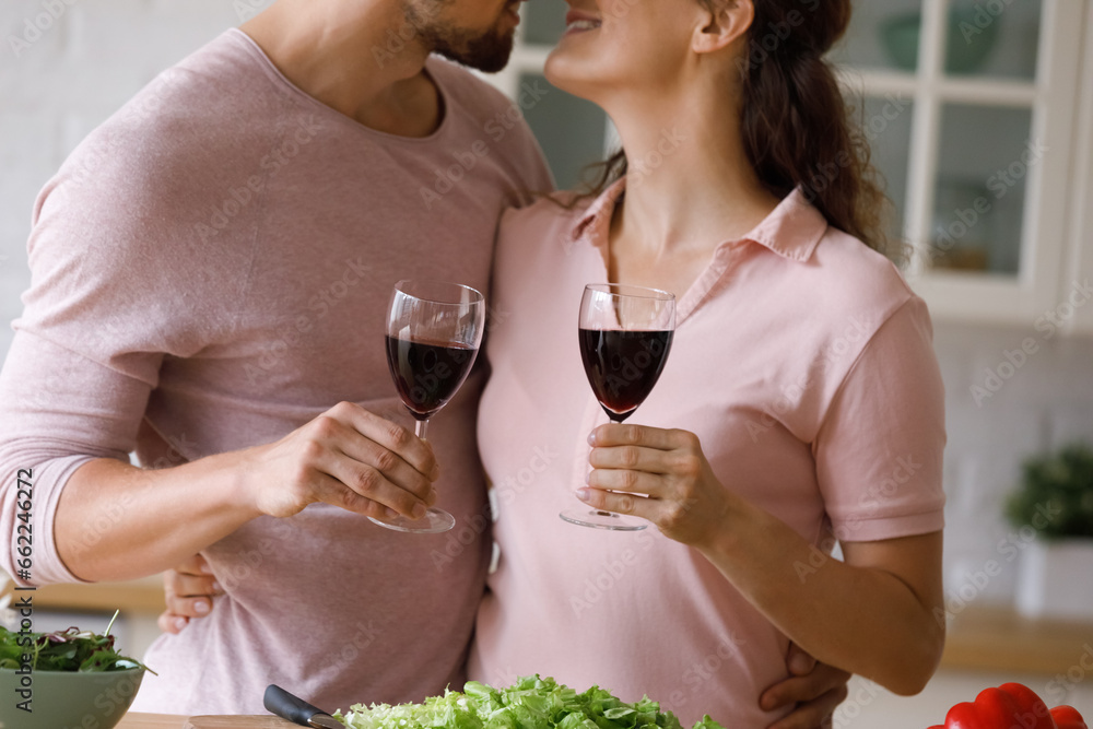 Φωτογραφία Happy dating, married couple in love drinking red wine, cooking dinner in kitchen, hugging with passion, tenderness, toasting alcoholic beverage, clinking glasses, kissing on lips