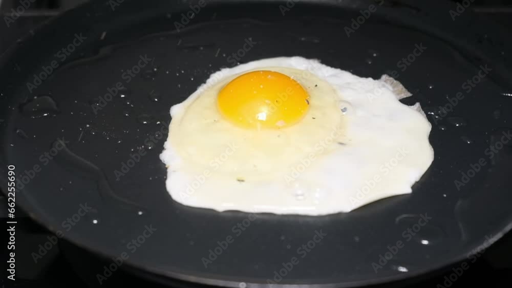 Sprinkle aromatic seasonings on the eggs in the pan. Frying an egg. Cooking concept Sprinkle aromatic seasonings on the eggs in the pan. Frying an egg. Cooking concept