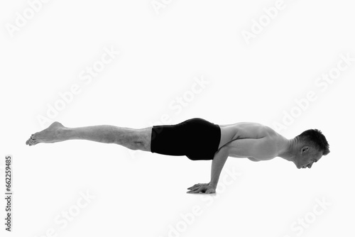 Mayurasana (Peacock Posture), Ashtanga yoga Side view of man wearing sportswear doing Yoga exercise against white background. Black and white image.