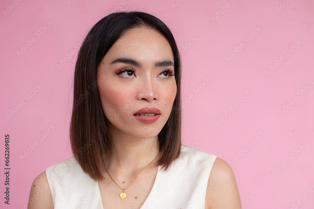 A typical asian woman with medium length hair wearing a cream sleeveless blouse. Against a pink background. A typical asian woman with medium length hair wearing a cream sleeveless blouse. Against a pink background.