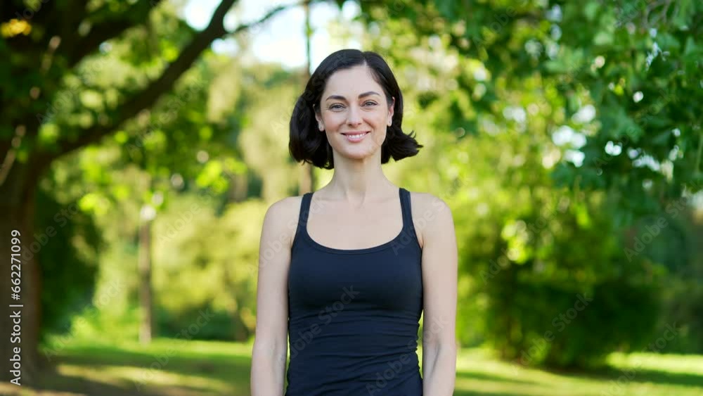Portrait of a young smiling brunette woman in an urban city park. Happy friendly sportswoman standing with arms crossed outdoors and looking at camera. Head shot of a female athlete after morning run Portrait of a young smiling brunette woman in an urban city park. Happy friendly sportswoman standing with arms crossed outdoors and looking at camera. Head shot of a female athlete after morning run