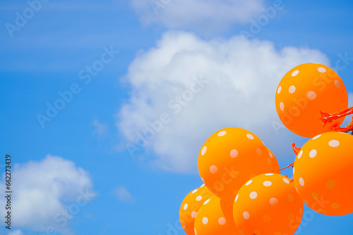 Orange balloons against a blue sky and cloud