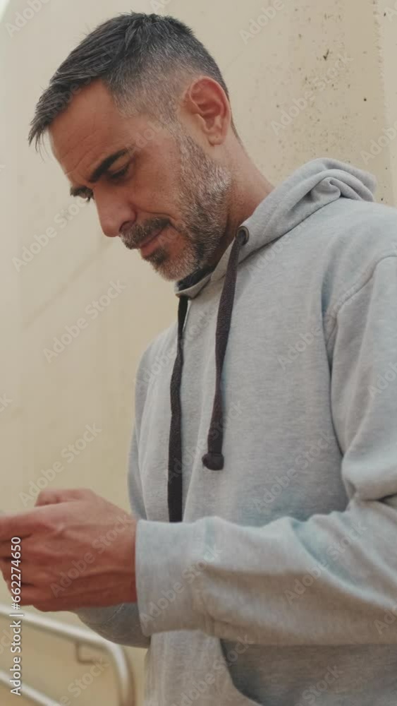 Close up, middle-aged man in sportswear typing an SMS message on his mobile phone after training Close up, middle-aged man in sportswear typing an SMS message on his mobile phone after training