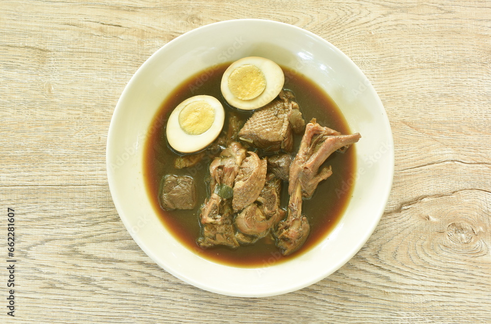 boiled half cut egg with braised duck meat and foot in Chinese herb brown soup on plate  