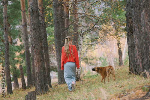 Young woman walking with her dog in autumn mountains