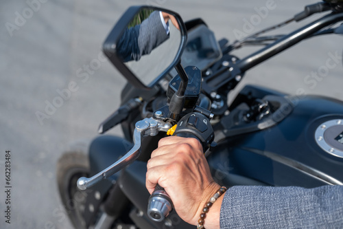 Caucasian man rides an electric motorcycle. Close-up of a man's hand pressing the gas on the steering wheel. 