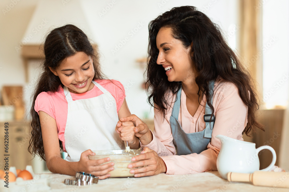 Joyful mommy and daughter enjoying cookie dough preparation in kitchen Joyful mommy and daughter enjoying cookie dough preparation in kitchen