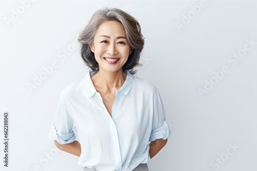 Portrait of Asian senior woman posing on white wall background.