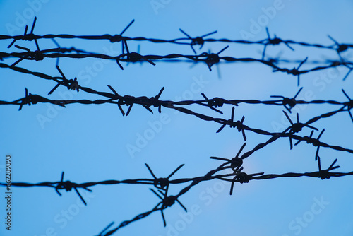 Tangle of barbed wire against the blue sky, In general, barbed wire is used as a security fence for buildings or national borders