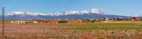 panorama of a typical western USA farm and barn with snowcapped mountains in the backgrund, in spring, Utah, USA.