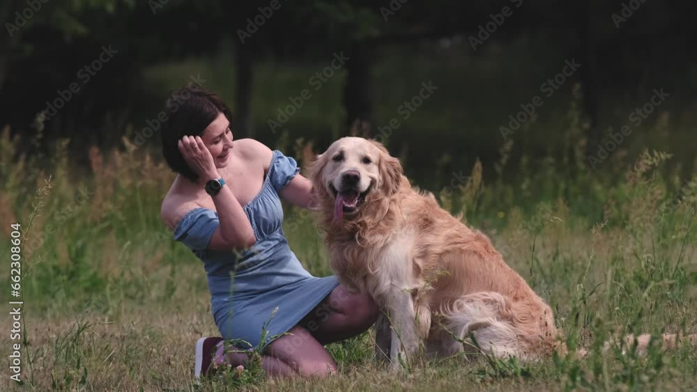 Pretty girl owner hugging golden retriever dog and smiling at nature. Young woman petting purebred pet doggy labrador at summertime Pretty girl owner hugging golden retriever dog and smiling at nature. Young woman petting purebred pet doggy labrador at summertime