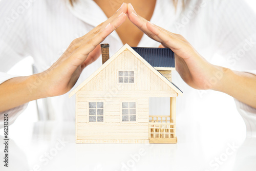 Close-up of woman's hands holding a small model house.