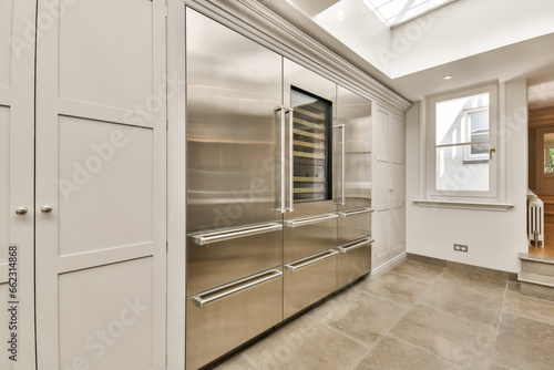 a modern kitchen with stainless steel appliances and white cupboards, in an open space that is well lit by the skylight