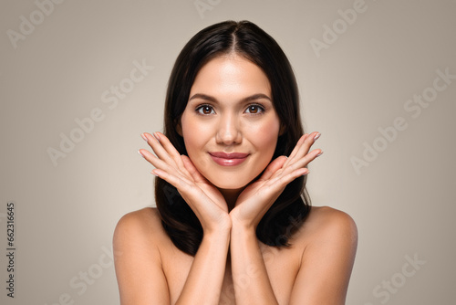 Calm pretty millennial european lady with perfect glowing skin touching hands to face