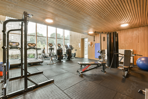 the inside of a home gym with weights, equipment and an exercise mat on the floor in front of the window
