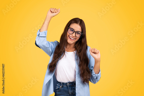Glad shocked european teen woman in glasses exuberant celebrates win, rise fists photo