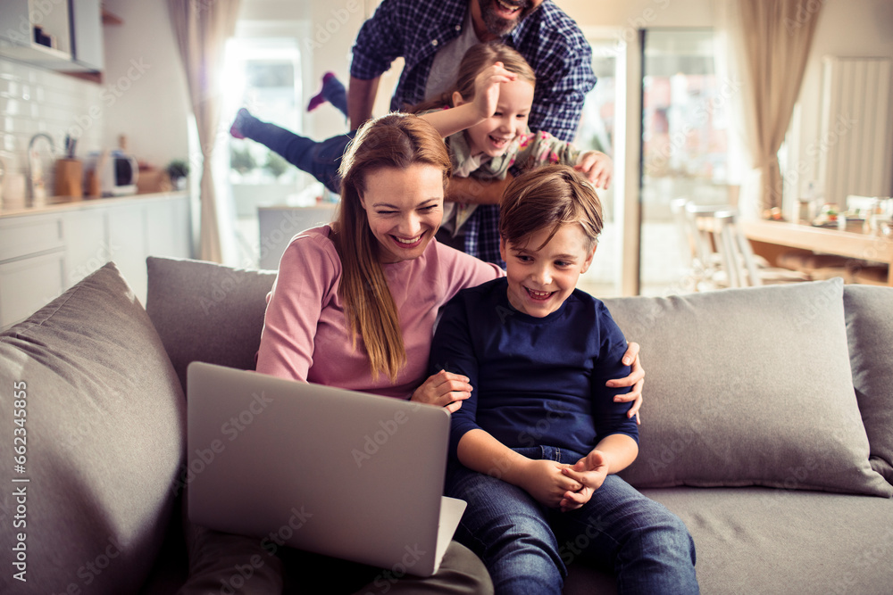 Young Caucasian family having fun and using a laptop at home Young Caucasian family having fun and using a laptop at home