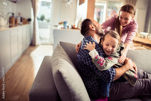 Young Caucasian family playing and having fun on the couch at home