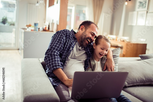 Young Caucasian father and daughter using a laptop at home