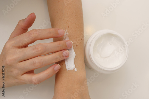 Foto A hand carefully applies white cream to the forearm, highlighting the concept of topical therapy and skincare