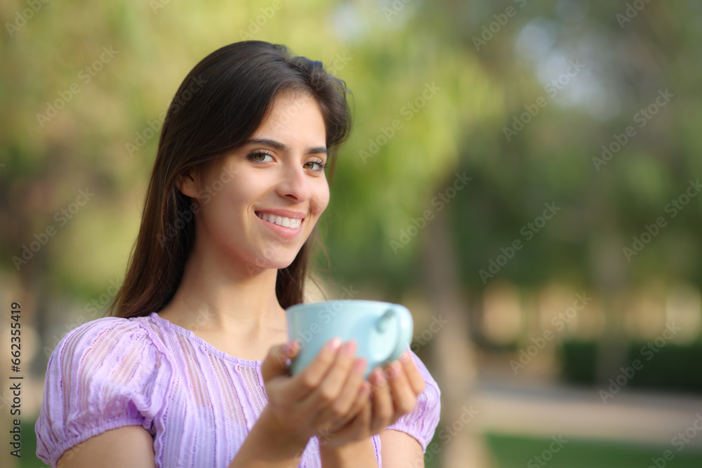 Happy woman looking at camera holding coffee cup Happy woman looking at camera holding coffee cup