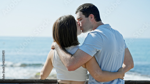 Beautiful couple hugging each other standing backwards kissing at seaside