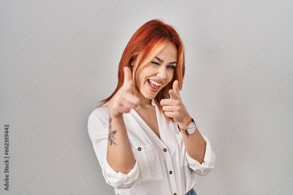 Young caucasian woman standing over isolated background pointing fingers to camera with happy and funny face. good energy and vibes. Young caucasian woman standing over isolated background pointing fingers to camera with happy and funny face. good energy and vibes.