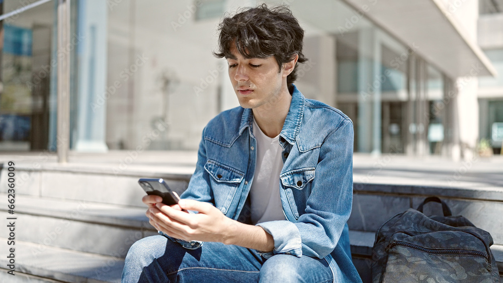 Young hispanic man student using smartphone sitting on stairs at university Young hispanic man student using smartphone sitting on stairs at university