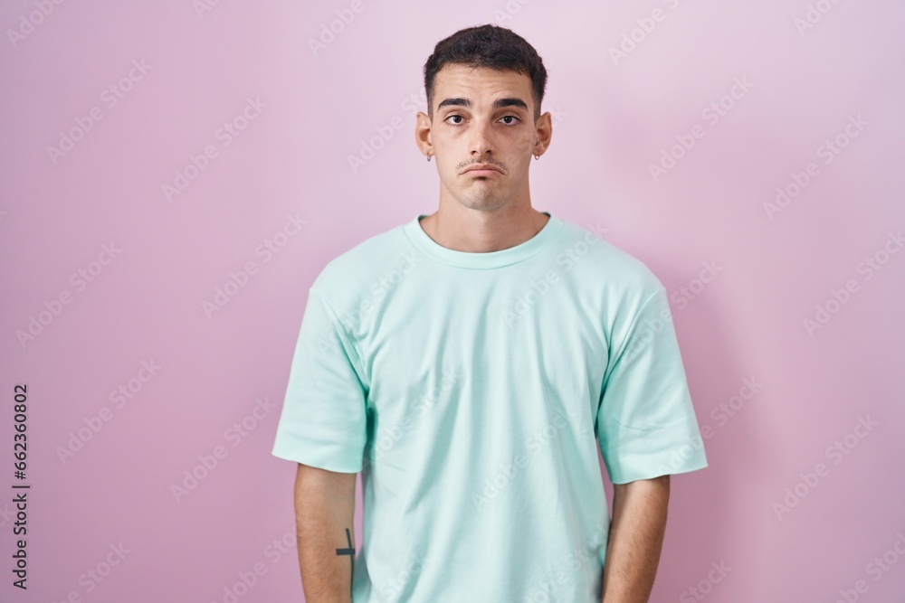 Handsome hispanic man standing over pink background depressed and worry for distress, crying angry and afraid. sad expression. Handsome hispanic man standing over pink background depressed and worry for distress, crying angry and afraid. sad expression.