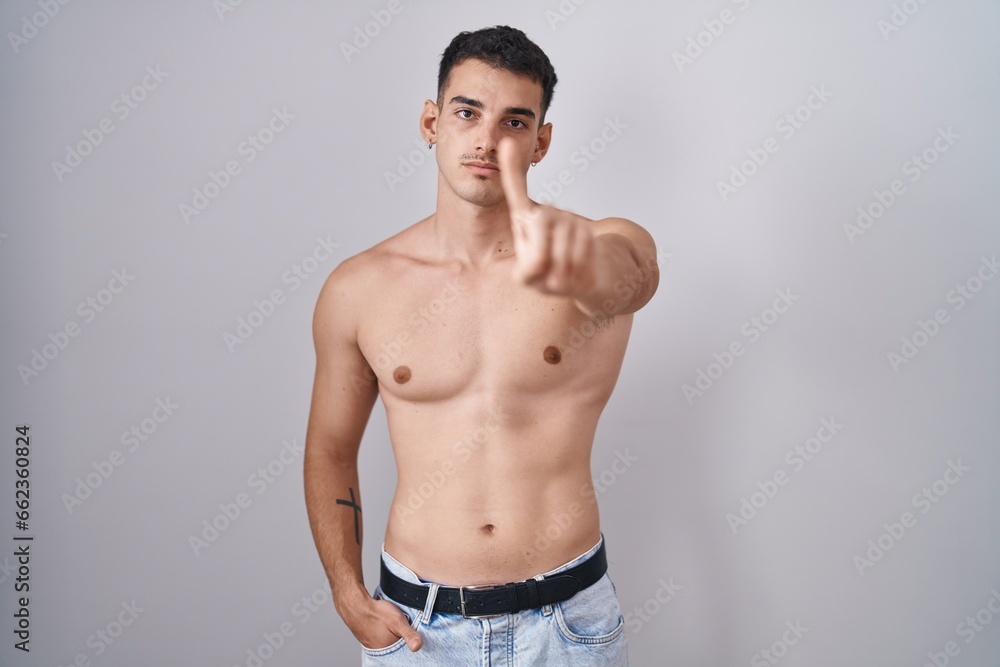 Handsome hispanic man standing shirtless pointing with finger up and angry expression, showing no gesture Handsome hispanic man standing shirtless pointing with finger up and angry expression, showing no gesture