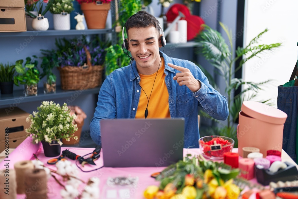 Handsome hispanic man working at florist shop doing video call smiling happy pointing with hand and finger Handsome hispanic man working at florist shop doing video call smiling happy pointing with hand and finger