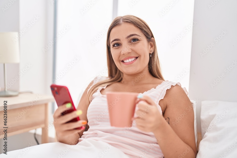 Young beautiful hispanic woman using smartphone drinking coffee at bedroom Young beautiful hispanic woman using smartphone drinking coffee at bedroom