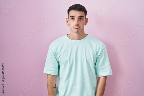Handsome hispanic man standing over pink background depressed and worry for distress, crying angry and afraid. sad expression.