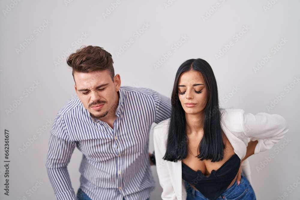 Young hispanic couple standing over white background suffering of backache, touching back with hand, muscular pain