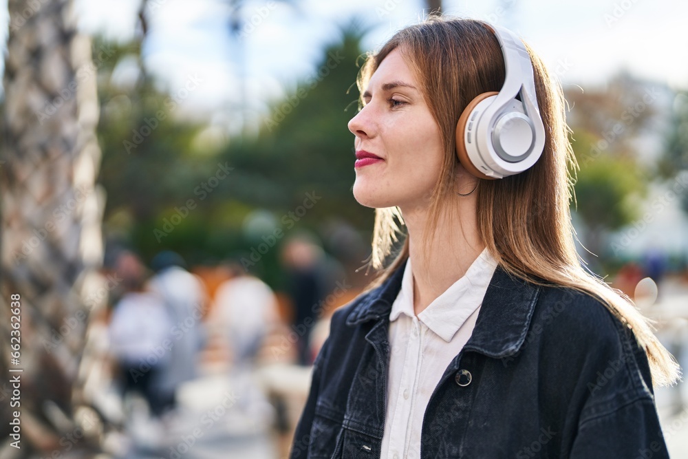 Young blonde woman listening to music at park