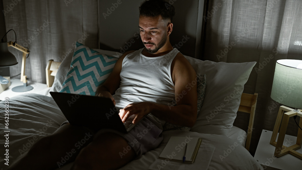 Young arab man using laptop sitting on the bed at bedroom Young arab man using laptop sitting on the bed at bedroom