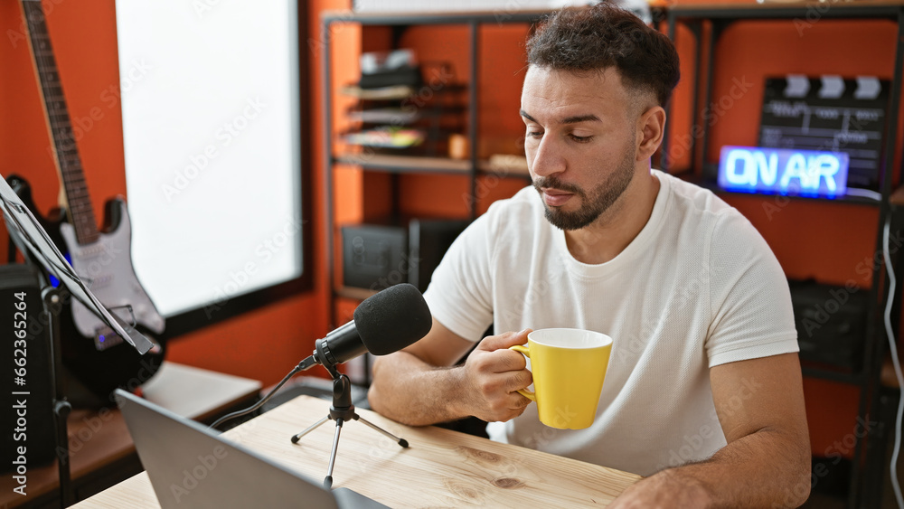 Young arab man musical reporter speaking on radio show drinking coffee radio studio Young arab man musical reporter speaking on radio show drinking coffee radio studio