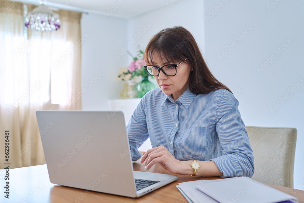 Middle aged business woman working on computer in home office Middle aged business woman working on computer in home office