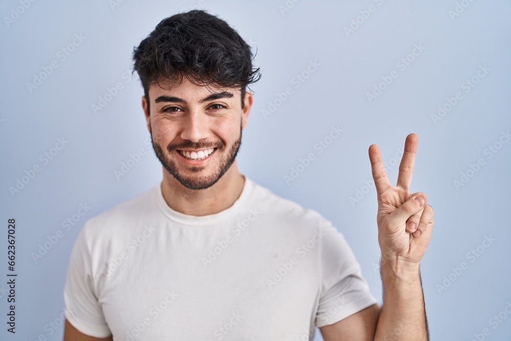 Hispanic man with beard standing over white background showing and pointing up with fingers number two while smiling confident and happy. Hispanic man with beard standing over white background showing and pointing up with fingers number two while smiling confident and happy.